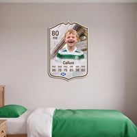 White and gold FC27 Icon personalised card displayed on a bedroom wall above a green and white bed