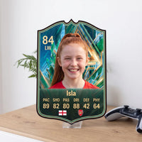 Emerald FC27 Wildcard personalised card displayed on an acrylic desk stand beside a plant and controller